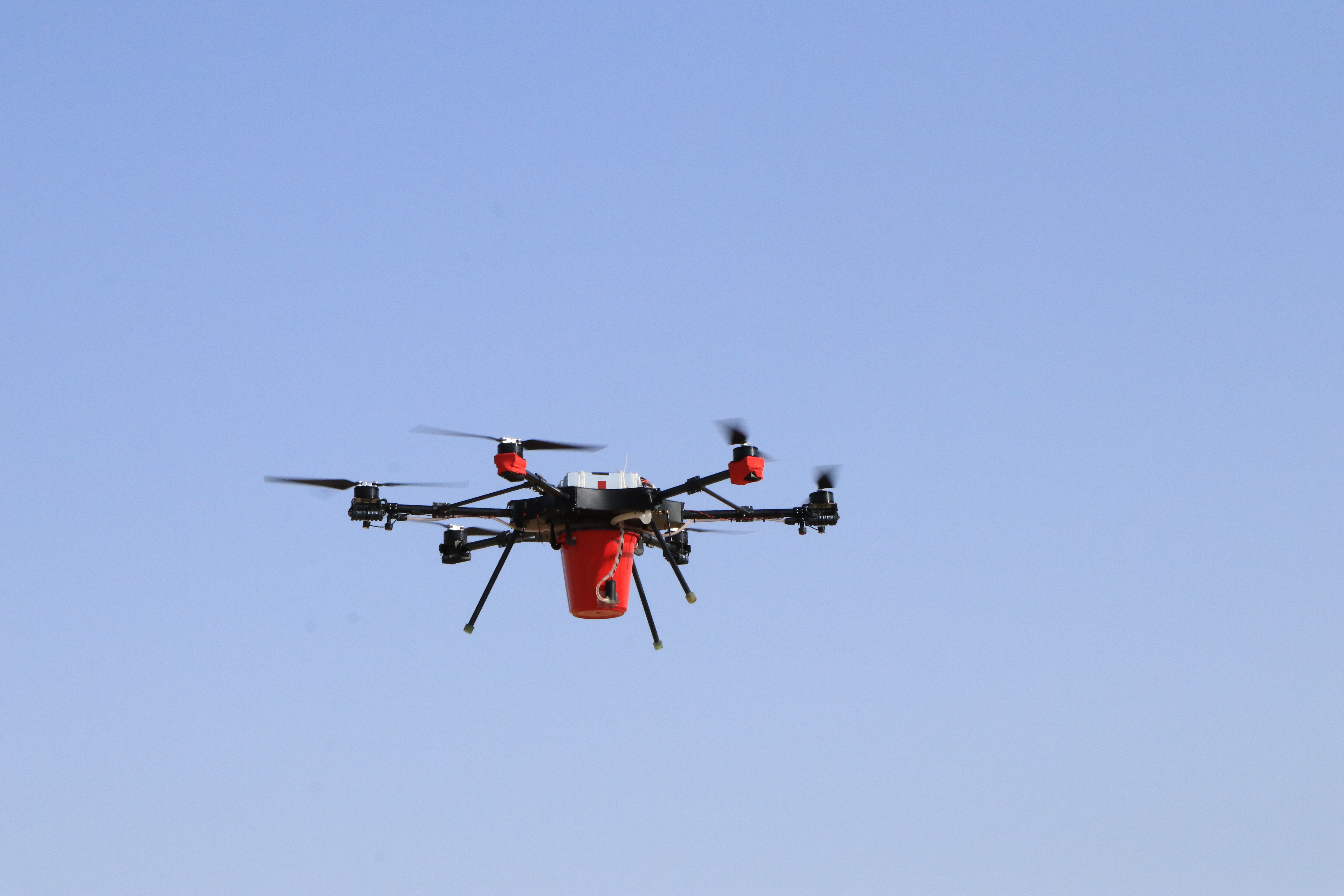 Hexacopter in flight carrying payload bucket
